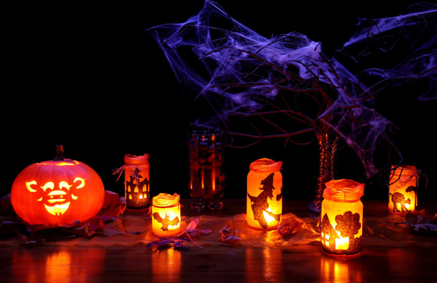 Halloween candles glowing in a dark room below eerie cobweb decorations