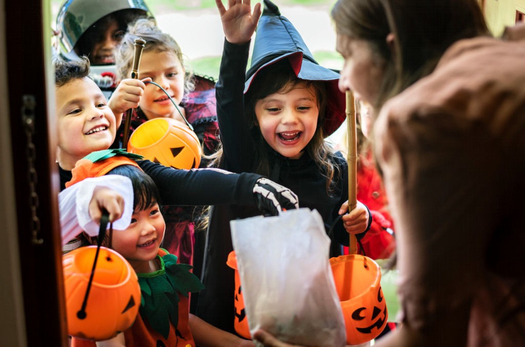 Trick-or-treating children gleefully accept candy from a happy homeowner