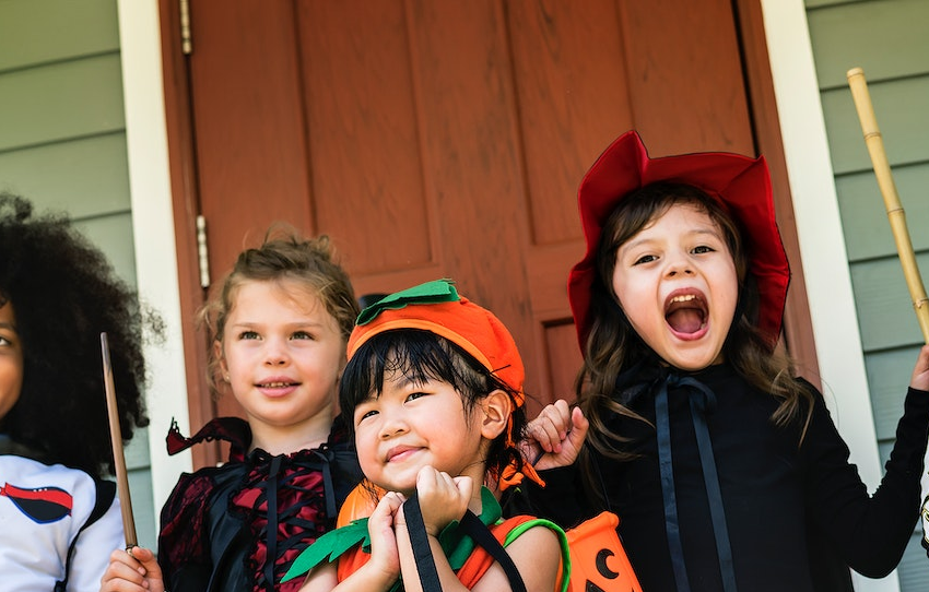 Trick-or-treaters smile in front of a house